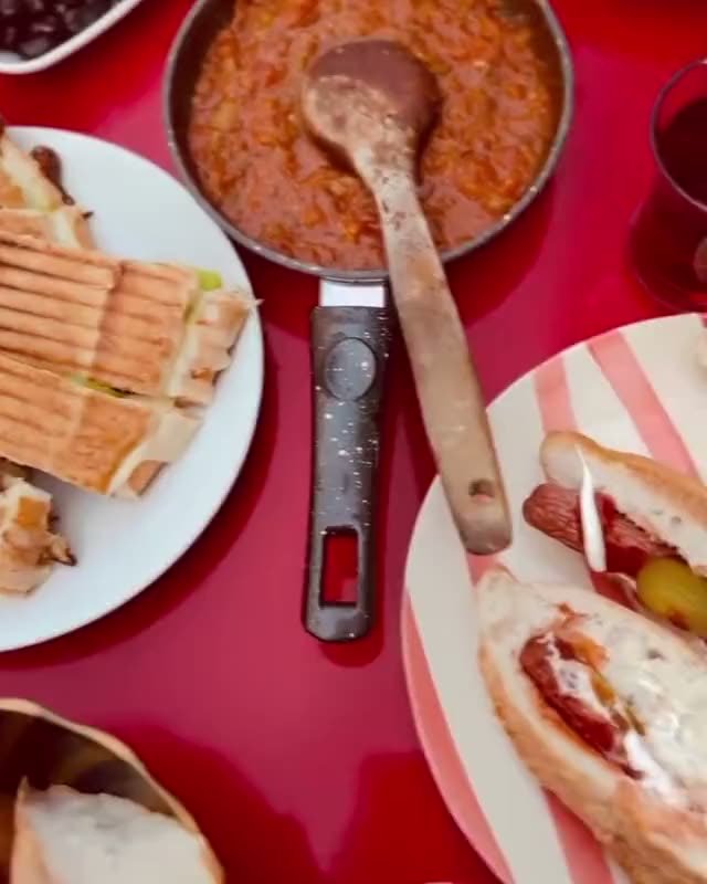 Kırmızı masada serpme kahvaltı: menemen, sucuklu yumurta, peynir, zeytin, turşu, çay.